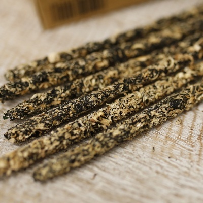 Bastões de incenso com ervas secas em superfície de madeira.