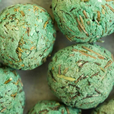 Bolas de banho verdes com pedaços marrons sobre superfície cinza