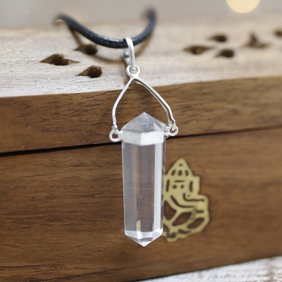 Colar com pendente de cristal transparente sobre caixa de madeira