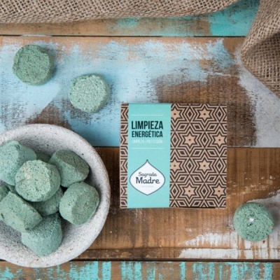 Pastilhas verdes e embalagem com padrão geométrico castanho e texto LIMPIEZA ENERGÉTICA Sagrada Madre