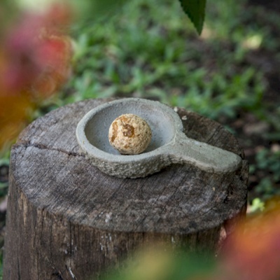 Prato de cerâmica cinzento com bola bege e manchas sobre tronco rústico