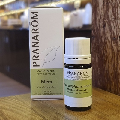 Frasco pequeno de óleo essencial de Mirra Pranarôm com caixa branca e verde sobre mesa de madeira.