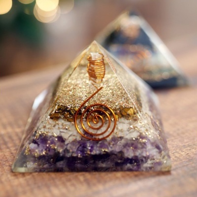 Pirâmides de resina com pedras roxas e fios de cobre sobre mesa de madeira