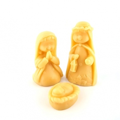 Três figuras de cera bege representando uma cena natalícia, com mãe, pai e bebé na manjedoura