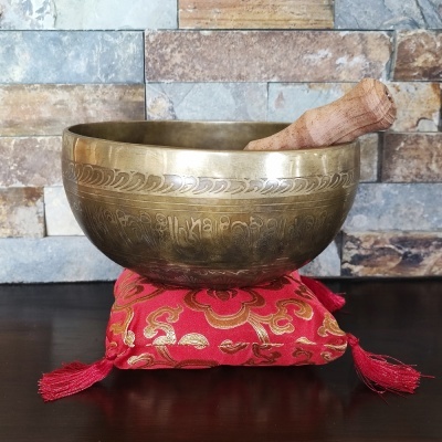 Tigela de metal dourado com almofada vermelha decorativa e bastão de madeira