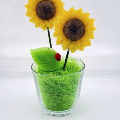 Arranjo decorativo de girassóis artificiais em copo de vidro com base verde e joaninha