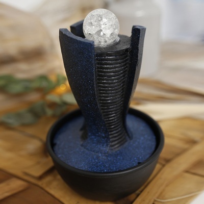 Fonte decorativa preta com esfera translúcida sobre areia azul