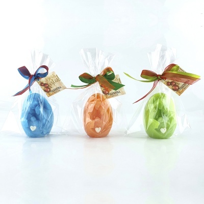 Três velas em forma de ovo nas cores azul, laranja e verde embaladas individualmente em celofane com laços coloridos e etiquetas VALENTINA