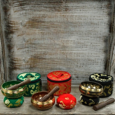 Tigelas tibetanas coloridas com suportes em tecido e madeiras para batê-las numa superfície de madeira