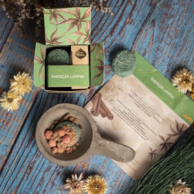 Produto de cuidado corporal com embalagem verde e folha, bola esfoliante, sabonete e folheto