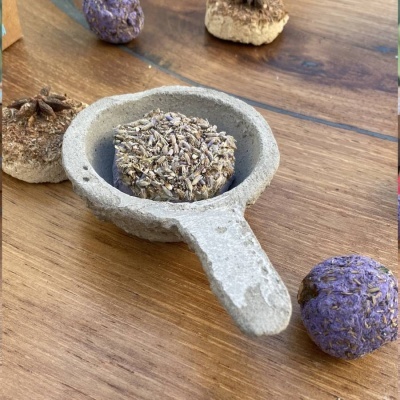 Sabonetes esfoliantes redondos com ervas secas em concha de pedra sobre mesa de madeira