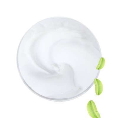 Creme branco num recipiente transparente com folhas verdes ao lado