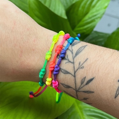 Pulseiras de fios coloridos no pulso com tatuagem de folhas