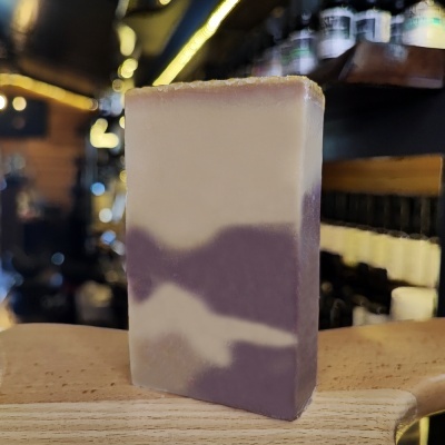 Sabonete branco e roxo sobre madeira em fundo com garrafas