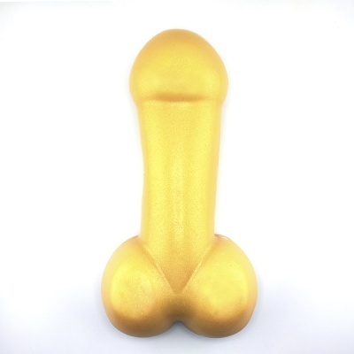 Objeto dourado com formato fálico sobre fundo branco