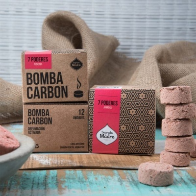 Caixas de carvão ativado para defumação e pastilhas empilhadas sobre superfície rústica com tecido ao fundo