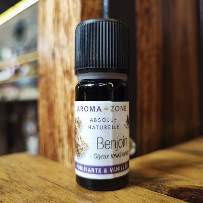 Frasco pequeno de óleo essencial Benjoin com rótulo branco e tampa preta sobre madeira