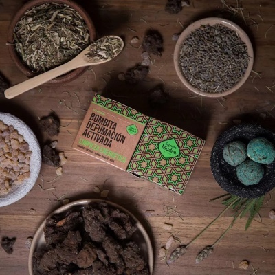 Caixa de papel decorada com ervas secas, resina e pedras azuis em potes em cima de uma mesa de madeira