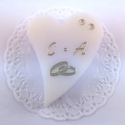 Bolo coração branco com decoração prateada e dois cristais sobre guardanapo rendado branco