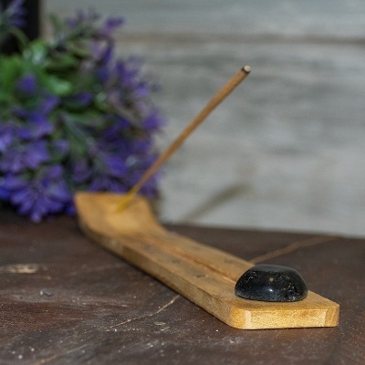 Suporte de incenso em madeira clara com pedra preta e pau de incenso aceso