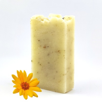 Sabonete bege claro com partículas ao lado de flor amarela