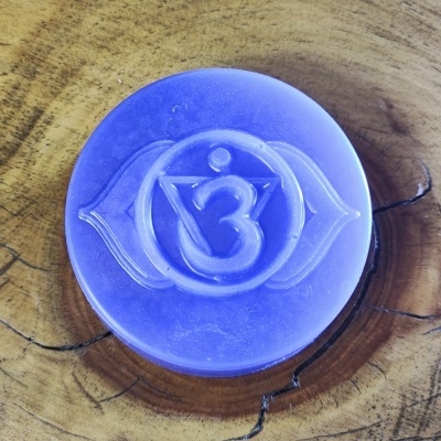 Sabonete roxo com símbolo gravado sobre placa de madeira