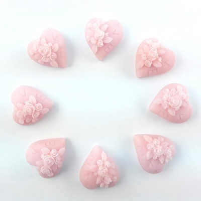 Oito sabonetes rosa em forma de coração com flores em relevo, dispostos em círculo