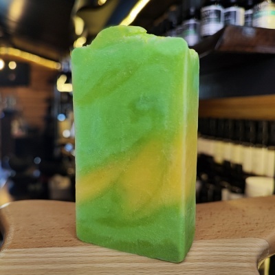 Barra de sabão verde e amarela retangular sobre suporte de madeira