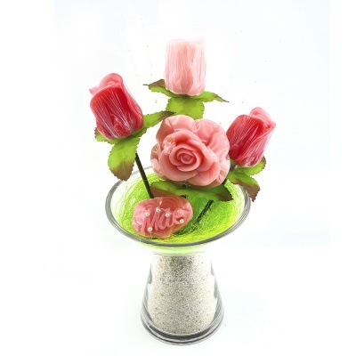 Arranjo com flores cor-de-rosa e vermelhas em vaso de vidro com areia e miolo verde