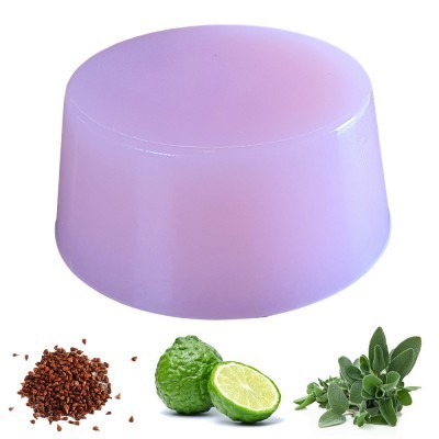 Sabonete lilás redondo junto a sementes castanhas, bergamota cortada e folhas verdes