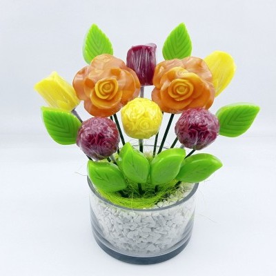 Arranjo decorativo de flores artificiais coloridas num recipiente transparente com pedras brancas