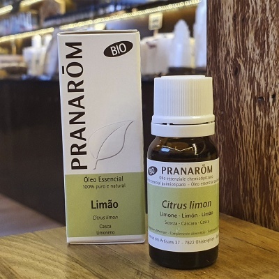 Frasco e embalagem de óleo essencial de limão Pranarôm BIO colocados sobre uma superfície de madeira