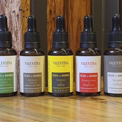 Frascos de óleo de barba Valentina de vidro âmbar com rótulos coloridos e conta-gotas pretos sobre superfície de madeira.