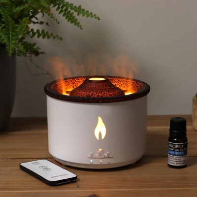 Difusor de aromas elétrico branco com textura castanha e chama acesa, frasco de óleo essencial Ancient Lavender e comando remoto