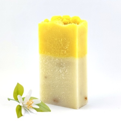 Sabonete amarelo e branco com flor branca ao lado