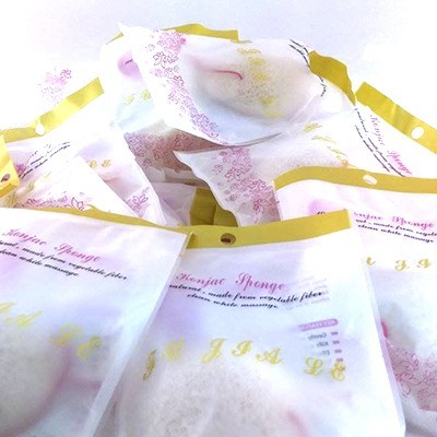 Pacotes de esponjas de banho macias com embalagem branca e detalhes amarelos.