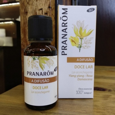 Frasco e caixa do óleo essencial Pranarôm Doce Lar em fundo de madeira