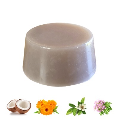 Sabonete castanho claro e ingredientes naturais como coco, calêndula, folhas verdes e flores lilases