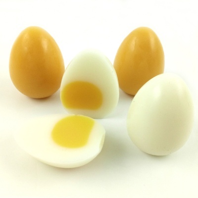 Cinco ovos, dois bege, dois brancos e um partido ao meio com gema visível sobre fundo branco.