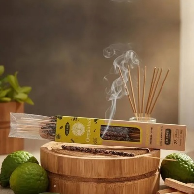 Incenso orgânico em vareta com embalagem amarela sobre base de madeira com limões verdes