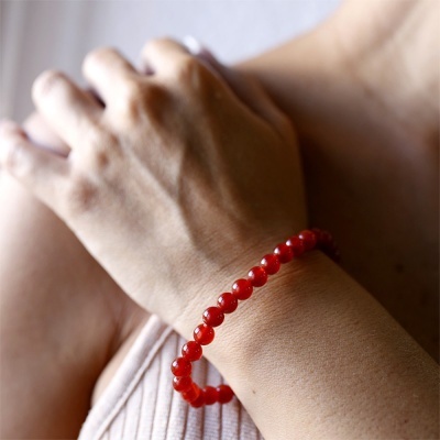 Pulseira de contas vermelhas translúcidas no pulso de uma pessoa