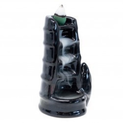 Incensário cascata preto em cerâmica com cone de incenso verde e fumaça descendo.