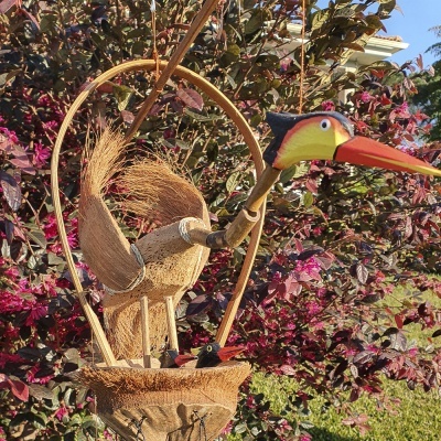 Escultura de pássaro colorido de madeira e fibras naturais com base e ninho ao ar livre