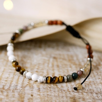 Pulseira colorida com contas e detalhes metálicos sobre madeira clara