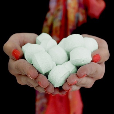 Mãos femininas seguram pastilhas brancas grandes com unhas vermelhas