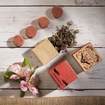 Conjunto de pastilhas vermelhas, ervas e caixas decorativas sobre madeira branca