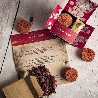 Conjunto amor e união com chocolates, flores secas e cartão explicativo sobre uma mesa branca de madeira.