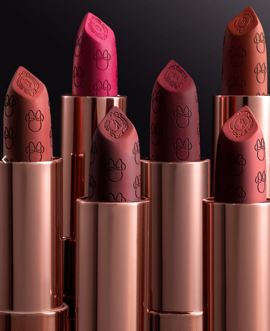 Seis batons com embalagem metálica rosa dourado e padrão gravado de cabeça de rato e brasão decorativo