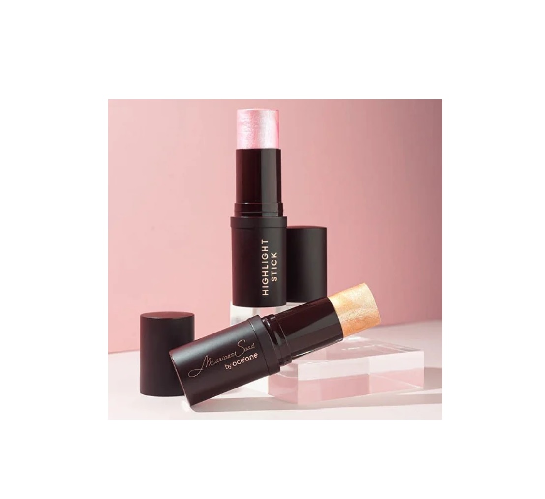 Duas sticks de maquilhagem preto com texto branco, um rosa e outro dourado, sobre fundo rosa claro.