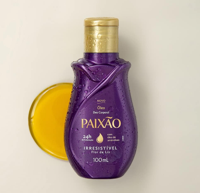 Frasco roxo de óleo corporal Paixão com tampa dourada e óleo amarelo ao lado